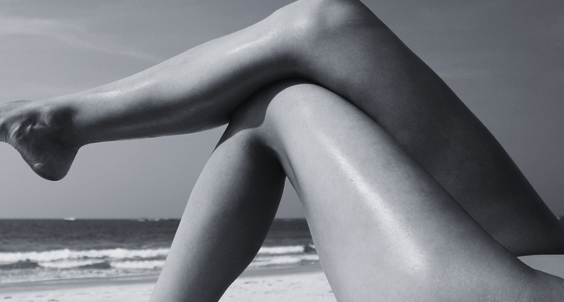 Woman's legs on the beach in summer sun - post-summer skin care and UV damage recovery