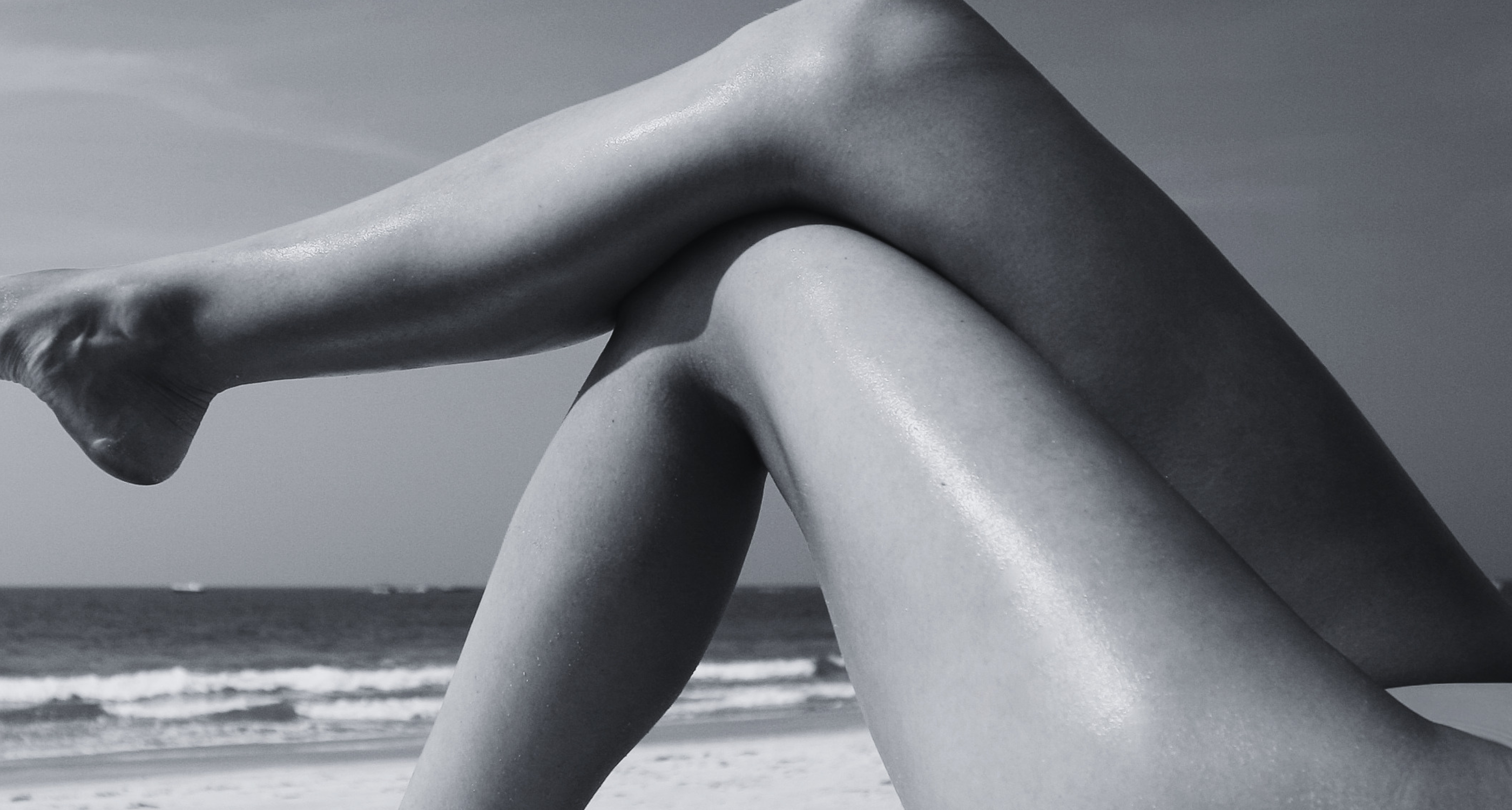 Woman's legs on the beach in summer sun - post-summer skin care and UV damage recovery